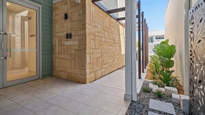 A modern building exterior with a brick wall, a glass door entrance, and a metal decorative panel. - Ocean View Retreat (Magenta)