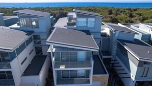 A modern multi-story residential building with a view of the ocean. - Ocean View Retreat (Magenta)