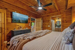 A wooden cabin bedroom with a bed, a ceiling fan, a mounted TV, and a wooden dresser. - *New Panoramic Smoky Mtn Views-Mins to Dollywood (Sevierville)