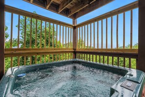 A hot tub with a wooden deck and railings, surrounded by greenery. - *New Panoramic Smoky Mtn Views-Mins to Dollywood (Sevierville)