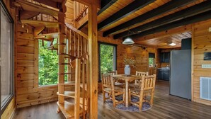 Een houten interieur met een wenteltrap, een eethoek met een tafel en stoelen, en een keuken.