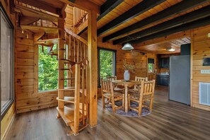 A wooden interior with a spiral staircase, a dining area with a table and chairs, and a kitchen area. - *New Panoramic Smoky Mtn Views-Mins to Dollywood (Sevierville)