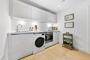 Una cocina moderna con lavadora integrada, microondas y fregadero.