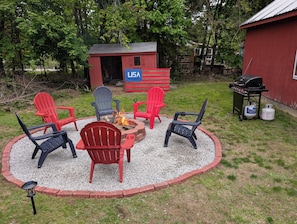 A circular seating area with Adirondack chairs, a fire pit, and a grill. - The Saco Valley Stay: Pet Friendly Retreat (Conway)