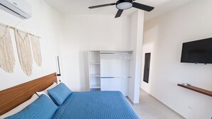 A bedroom with a bed, a ceiling fan, a wardrobe, and a TV.