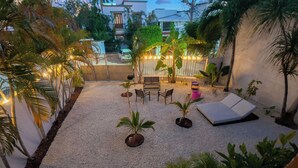 A patio area with a seating arrangement, potted plants, and a white wall.