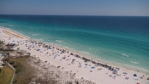 A beach with a long stretch of sand, umbrellas, and people. - Gulf-Front Sandestin Studio | Balcony Views, Pool & Beach Access | Beachside II 4268 (Miramar Beach)