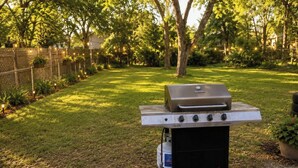 A portable grill with a side burner and a propane tank.