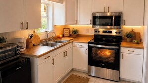Una cocina moderna con gabinetes blancos, electrodomésticos de acero inoxidable y encimera de madera.