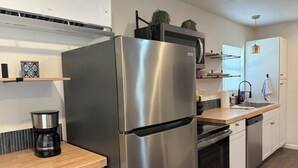 Une cuisine moderne dotée d’un réfrigérateur en acier inoxydable, d’une machine à café et de plans de travail en bois.
