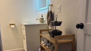 Une salle de bain équipée d’un lavabo, d’un porte-serviettes et d’une étagère en bois.