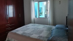 A bedroom with a bed, a wardrobe, a window, and an air conditioning unit. - Entire house 350m from Ingleses Beach, sleeps up to 5 people. (Florianópolis)