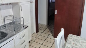 A kitchen with white cabinets, a sink, and a clock on the wall. - Entire house 350m from Ingleses Beach, sleeps up to 5 people. (Florianópolis)