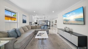 Een moderne woonkamer met een modulaire bank, een salontafel en een grote televisie.