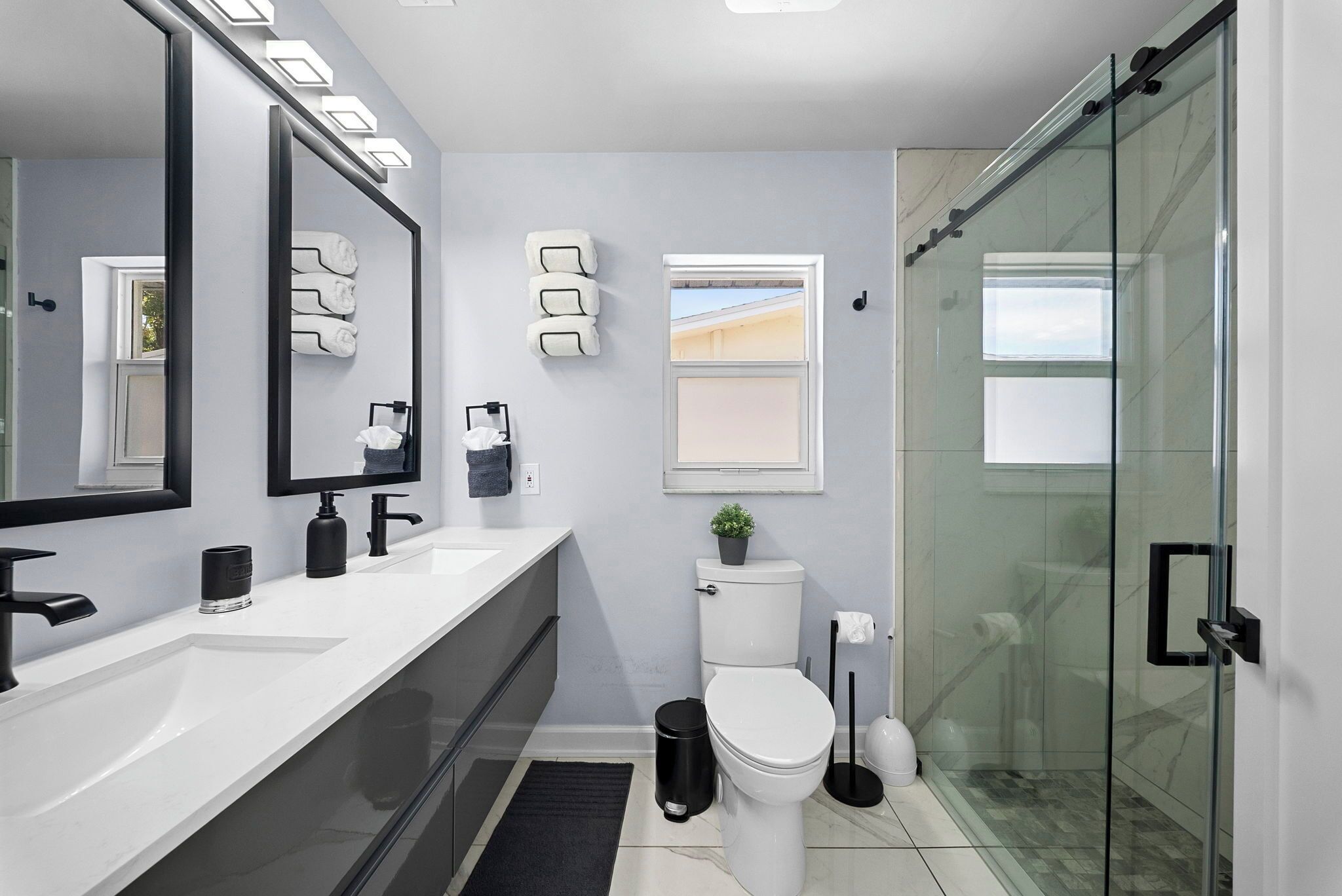 A modern bathroom with a glass shower enclosure, a large mirror, and a white sink.