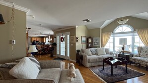 A spacious living room with a fireplace, a dining area, and a kitchen in the background. - Relax & Recharge at the Northern Gateway – Lakeview Retreat in Rouses Point, NY (Rouses Point)