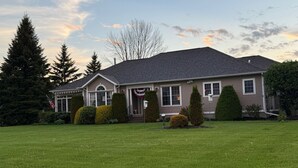 A two-story house with a front porch, a flag, and a well-maintained lawn. - Relax & Recharge at the Northern Gateway – Lakeview Retreat in Rouses Point, NY (Rouses Point)