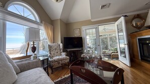 A living room with a sofa, armchair, TV, dining table, and a fireplace. - Relax & Recharge at the Northern Gateway – Lakeview Retreat in Rouses Point, NY (Rouses Point)