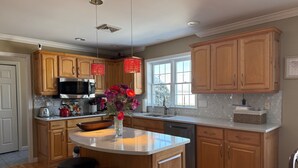 A kitchen with wooden cabinets, a microwave, a sink, and a vase with flowers. - Relax & Recharge at the Northern Gateway – Lakeview Retreat in Rouses Point, NY (Rouses Point)