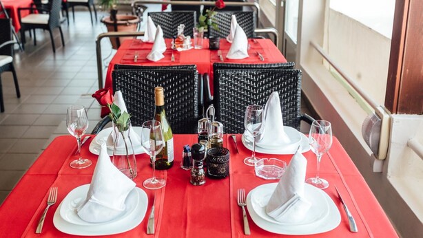 A restaurant with red tablecloths, white napkins, and black wicker chairs. - Azzurro Hotel Bijela, Herceg Novi (Bijela)