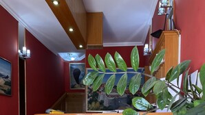 A lobby with a wooden reception desk, a brown leather chair, and a large green plant. - Azzurro Hotel Bijela, Herceg Novi (Bijela)