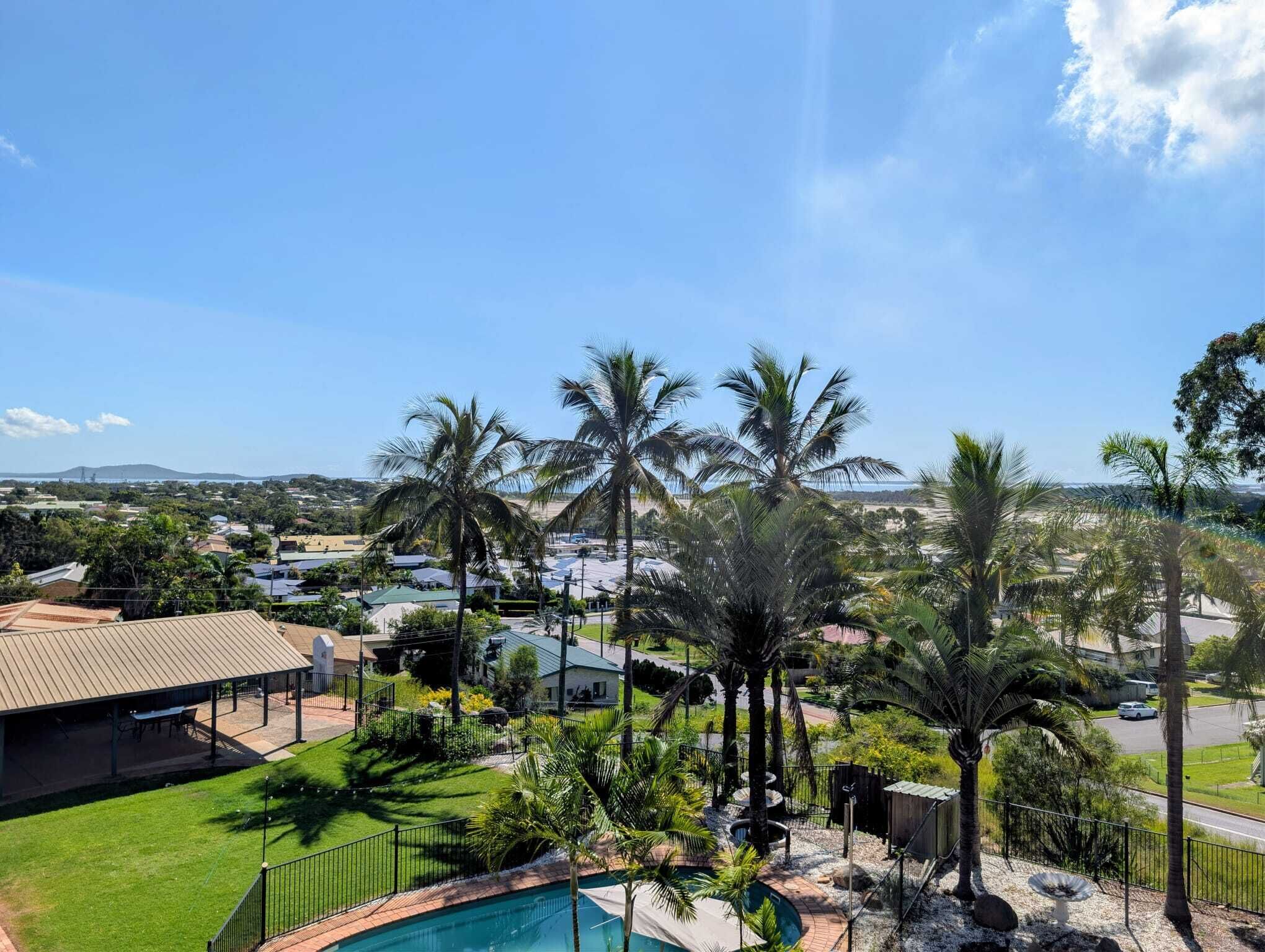 Zona residencial con piscina, palmeras y casas.