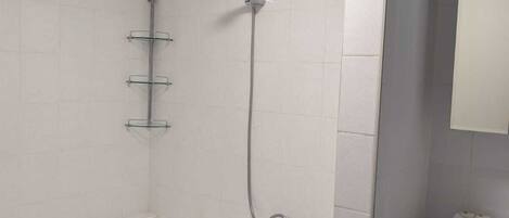 Un baño con una bañera blanca, ducha y tocador con espejo.