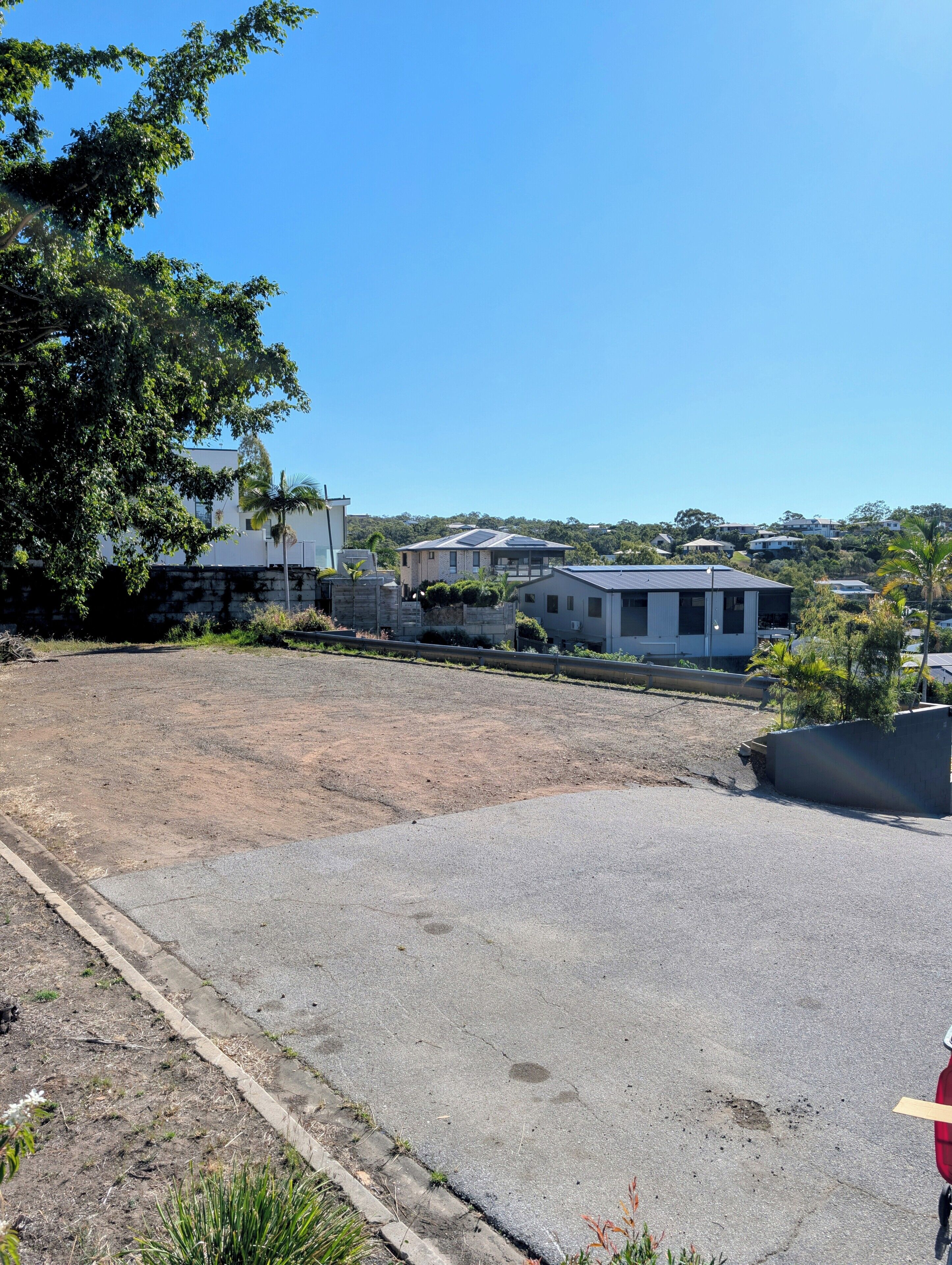 A residential area with houses, a paved parking lot, and a clear blue sky.