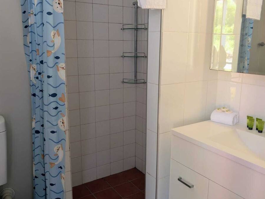 Ein Badezimmer mit Dusche, Toilette, Waschbecken und Spiegel.