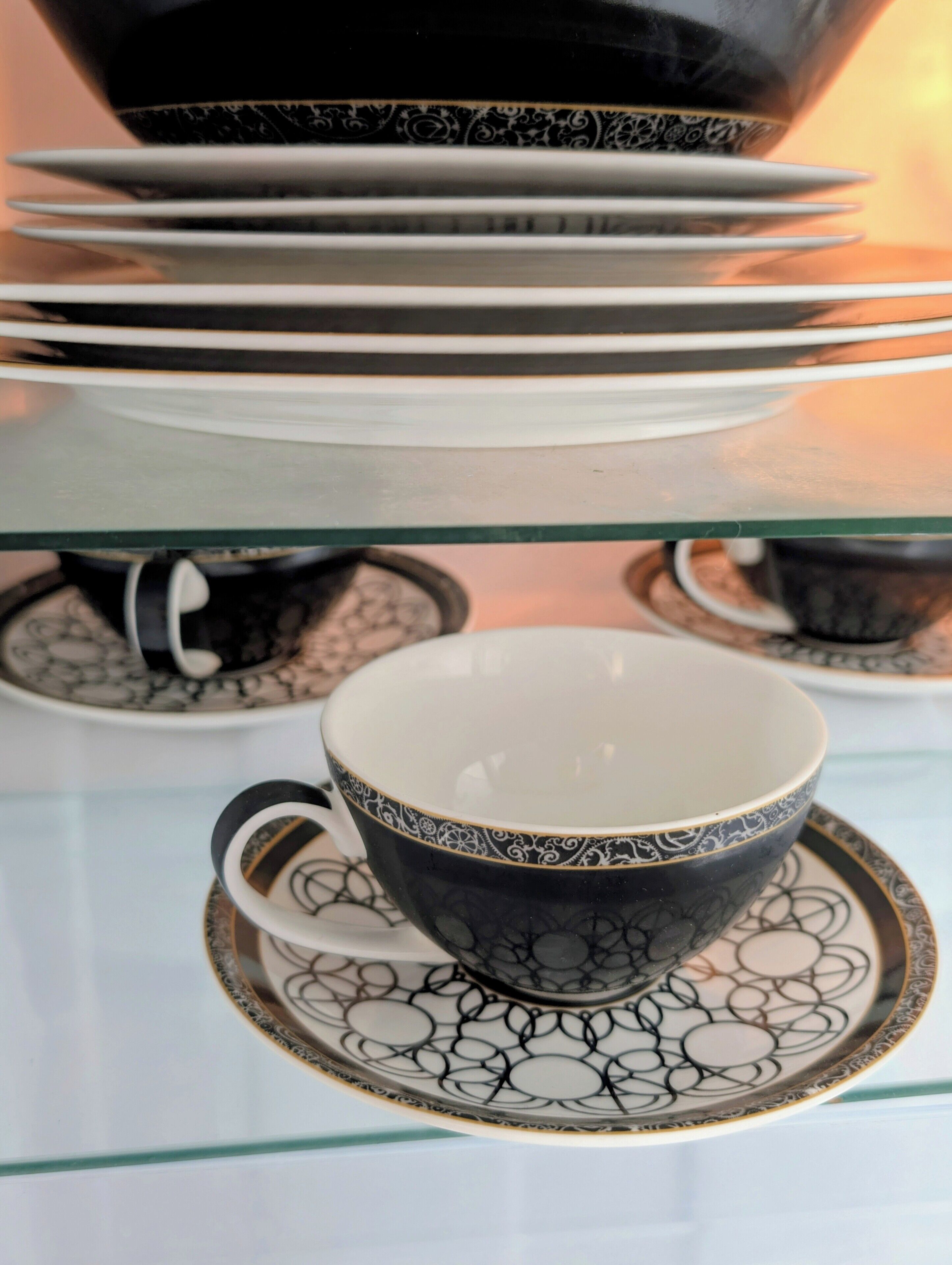 Una pila de tazas y platillos blancos y negros con un diseño.