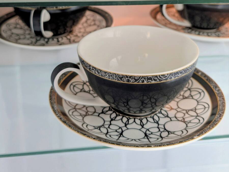 Una pila de tazas y platillos blancos y negros con un diseño.