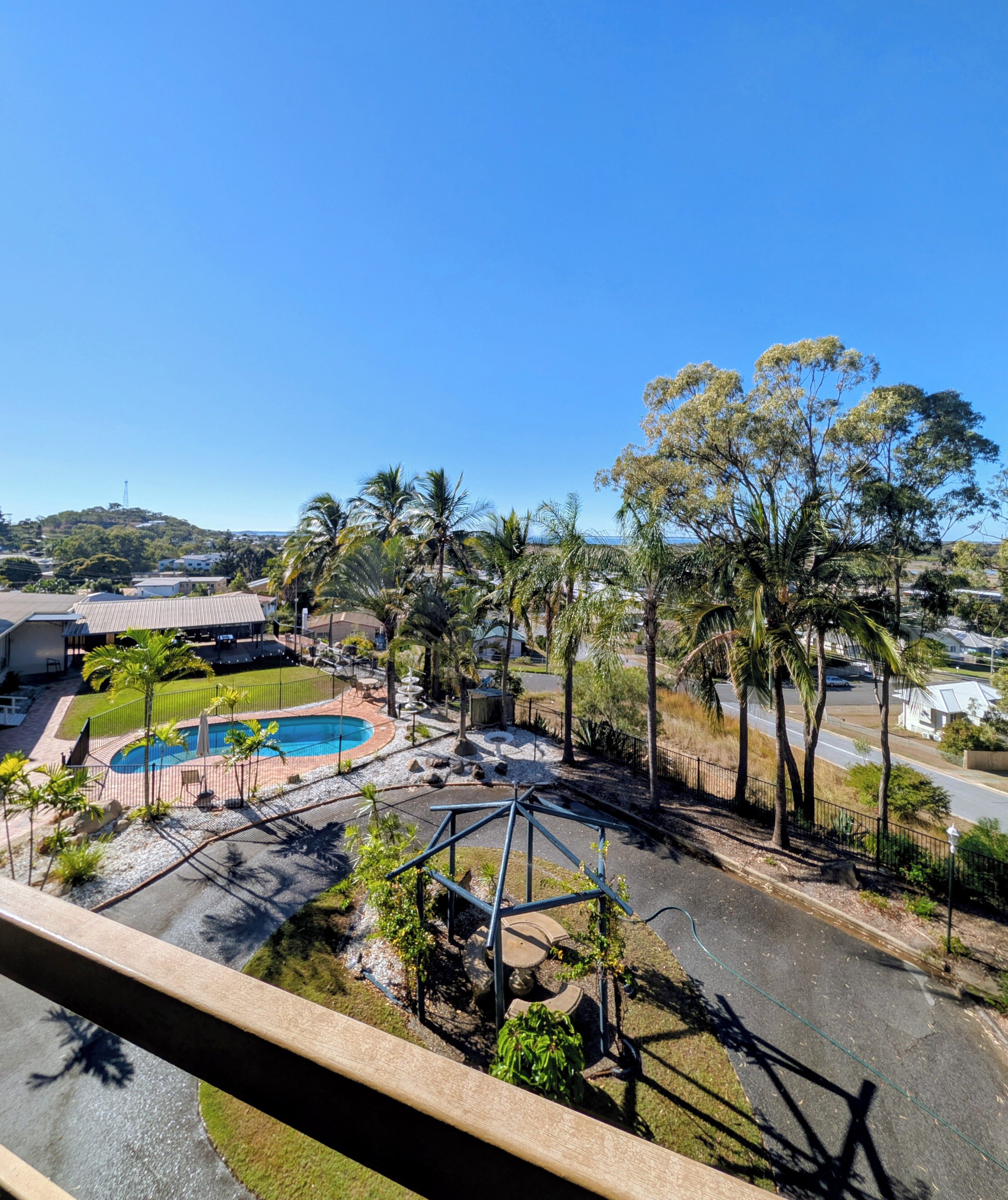 Zona residencial con piscina, palmeras y vistas a una colina.