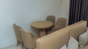 Een moderne kamer met een beige bank, een ronde tafel en passende stoelen.