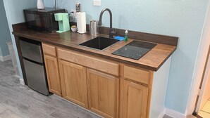 Una cocina equipada con microondas, cafetera, lavabo y refrigerador.