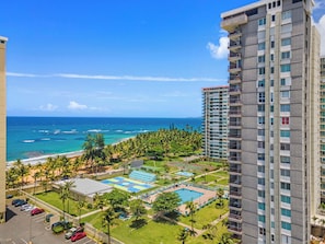 A high-rise hotel with a view of the ocean, a swimming pool, and a tennis court. - Luxury Apartment Luquillo | Ocean View Suite (Luquillo)