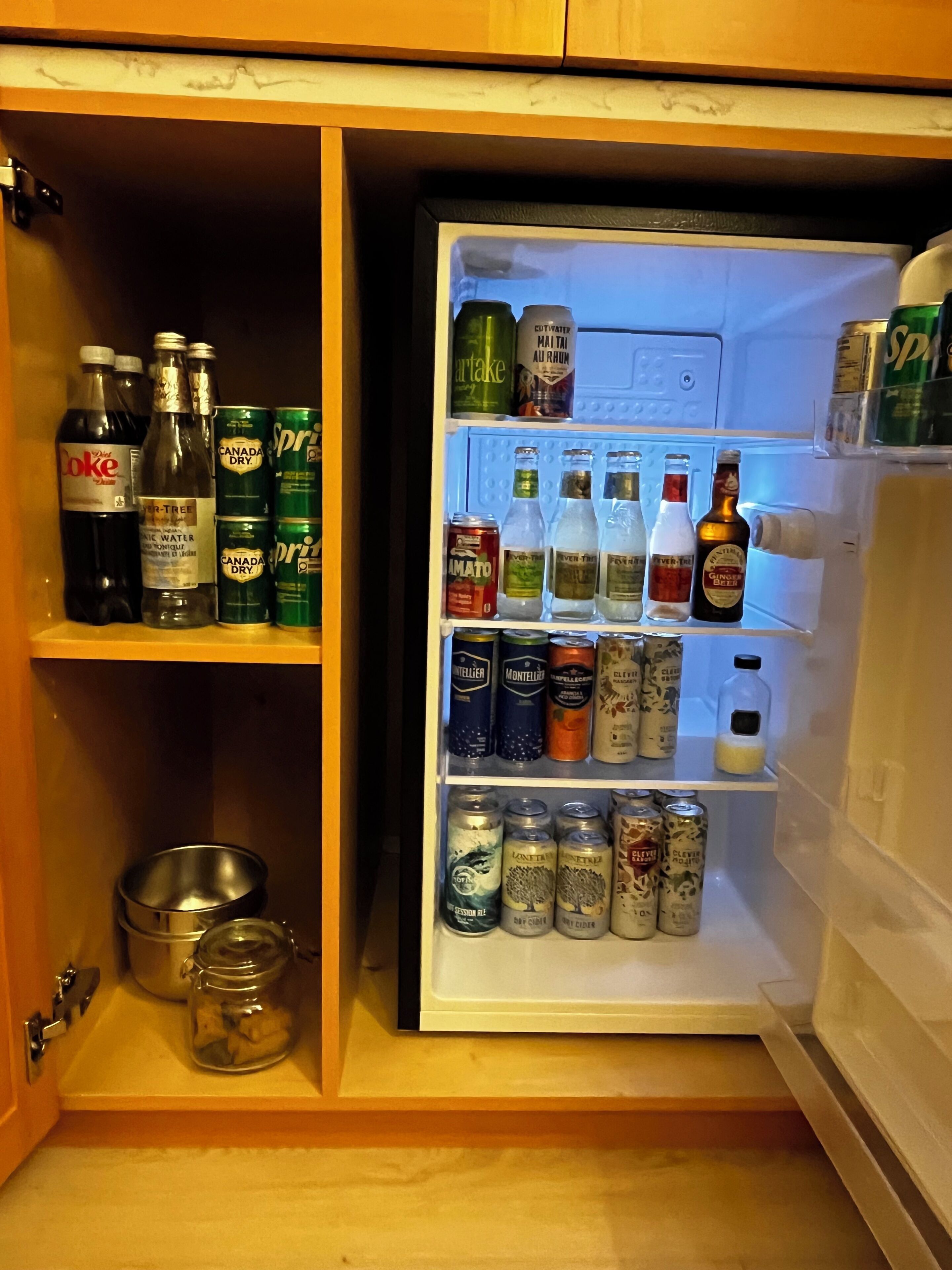 A refrigerator stocked with various beverages including sodas, beers, and spirits.