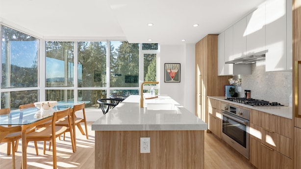 A modern kitchen with wooden cabinets, a central island, and large windows.