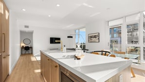 A modern kitchen with a large island, wooden cabinets, and a built-in oven.