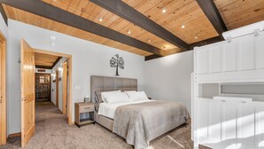 A bedroom with a bed, bedside table, and a wall-mounted tree decoration. - Alpine Pines | Deck | BBQ | Community Amenities (Kings Beach)