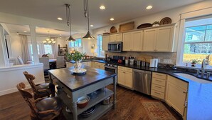 A modern kitchen with a central island, stainless steel appliances, and a view of the outdoors. - The Blue House: Spacious home w/ patio, fenced yard, views, close to everything (Bozeman)