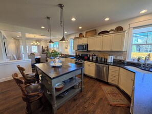 A modern kitchen with a central island, stainless steel appliances, and a view of the outdoors.