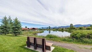 A bench by a lake with a clear view of mountains in the distance. - The Blue House: Spacious home w/ patio, fenced yard, views, close to everything (Bozeman)