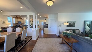 A spacious kitchen with white cabinetry, a dining area with a wooden table and chairs, and a living area with a sofa and a side table. - The Blue House: Spacious home w/ patio, fenced yard, views, close to everything (Bozeman)