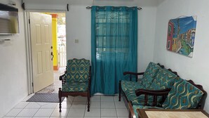 Un salon avec un canapé, un fauteuil, un téléviseur et un tableau accroché au mur.