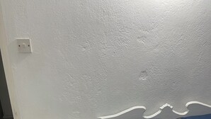 Une chambre à coucher avec un lit, une table de chevet et une prise électrique au mur.
