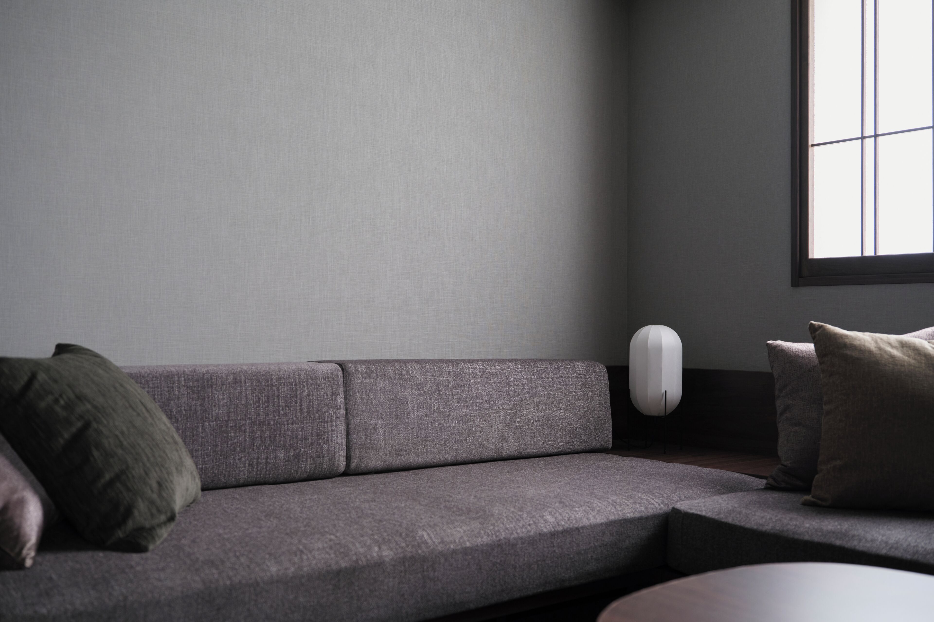 Un saló modern amb un sofà gris, una taula de centre rodona i una làmpada minimalista.