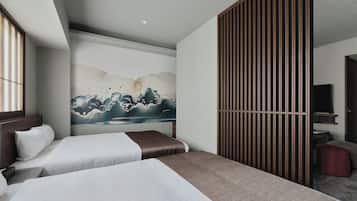 Quarto de hotel com duas camas, uma pintura grande de ondas, uma porta de correr e uma televisão.
