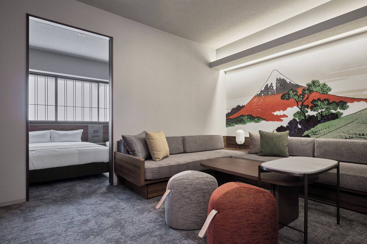 Una habitación de hotel moderna con sofá, una mesita, una silla y una cama con ventana.
