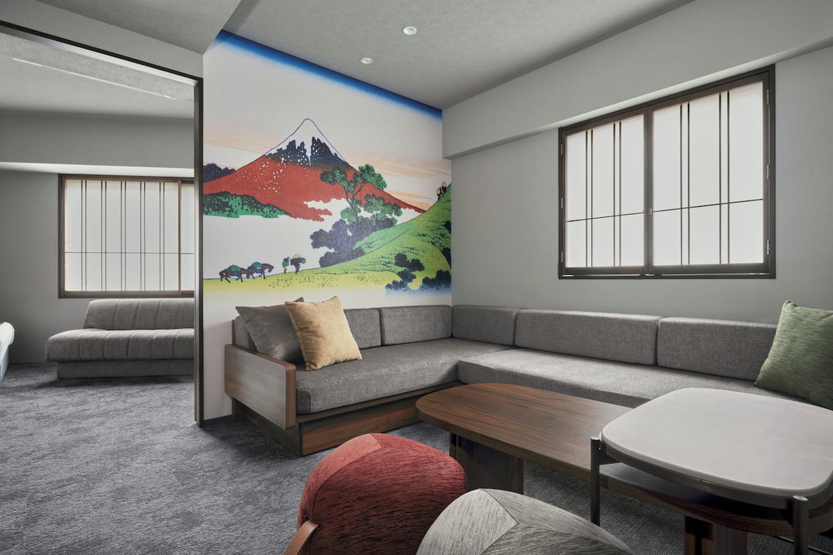 Una sala de estar moderna con un sofá seccional, una mesa de centro y un mural de un paisaje montañoso.