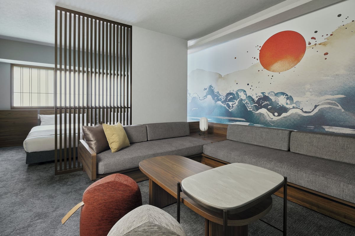 Una sala moderna con un sofá modular, una mesa de centro de madera y un separador de ambientes de estilo japonés.